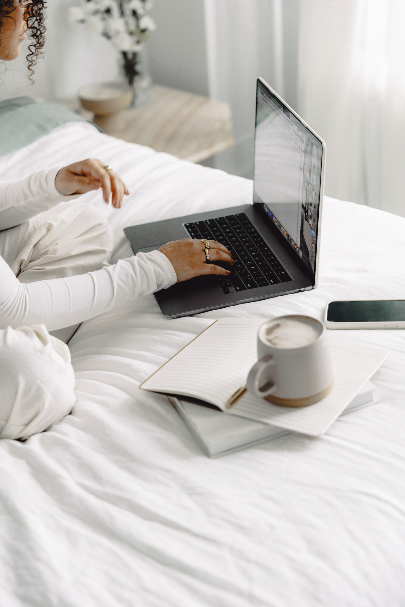 “Woman working on laptop in bed with coffee and notebook, planning how to grow her email list”