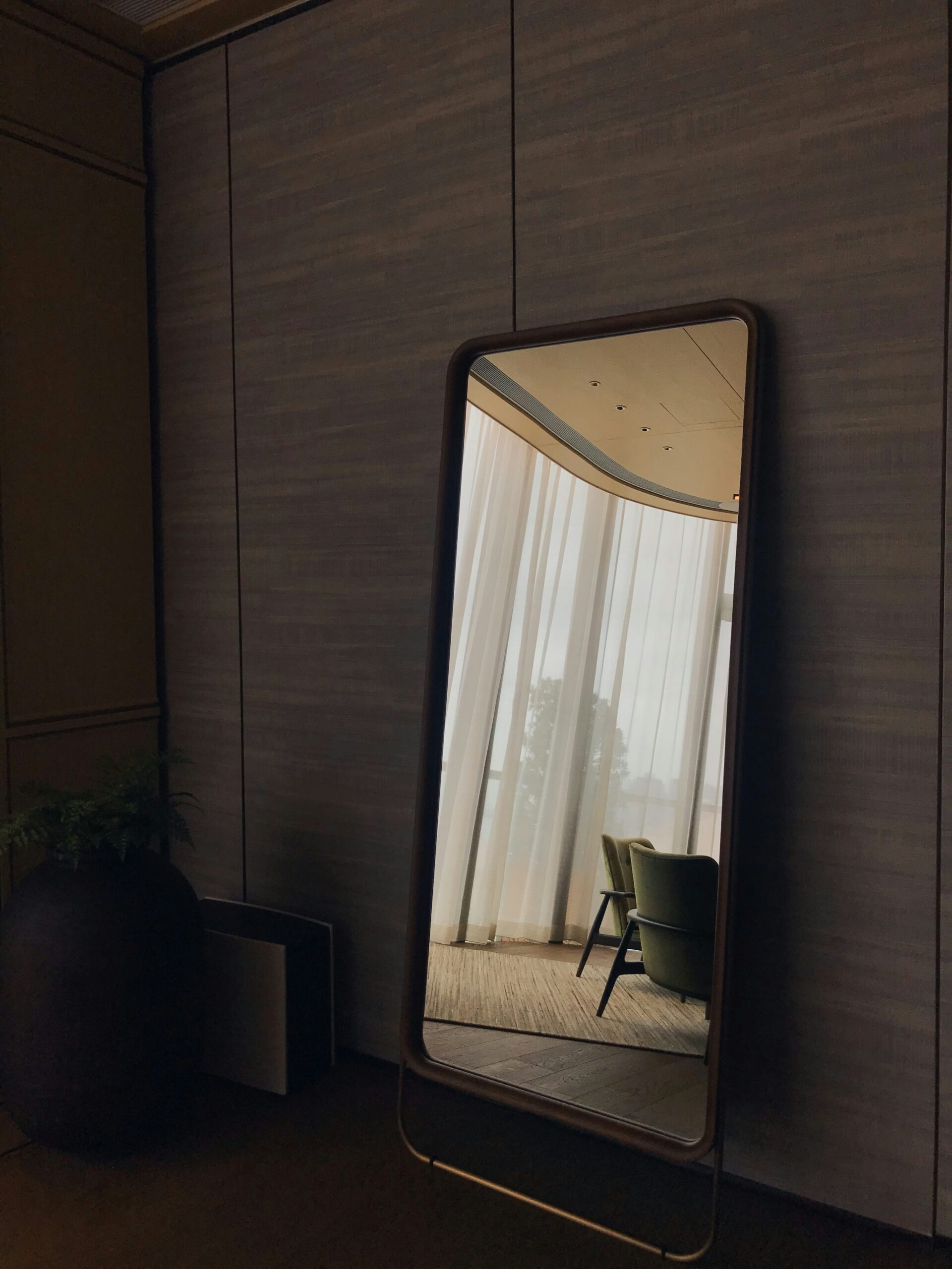 A mirror reflecting two chairs and sheer curtains, symbolizing introspection and becoming who God has called you to be.